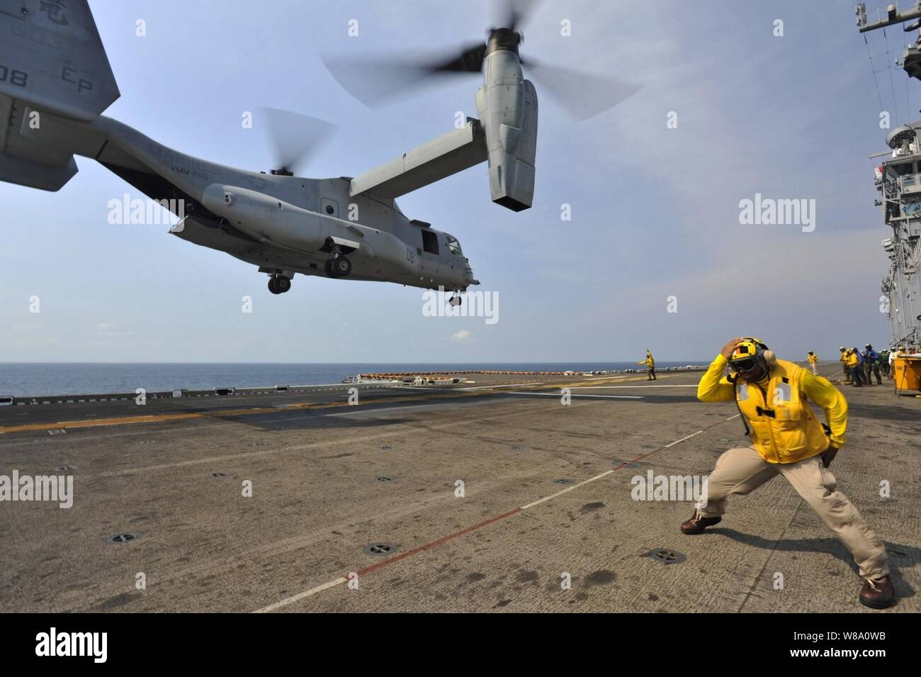 Chief Petty Officer Patrick Dewberry braces himself ¬against the rotor wash of a MV-22 Osprey launching from the deck of the amphibious assault ship USS Bonhomme Richard (LHD 6) in the Gulf of Thailand on Feb. 19, 2013.  The Bonhomme Richard Amphibious Ready Group is deployed in the U.S. 7th Fleet area of responsibility and is taking part in Cobra Gold 2013, a Thai-U.S. co-sponsored multinational joint exercise. Stock Photo