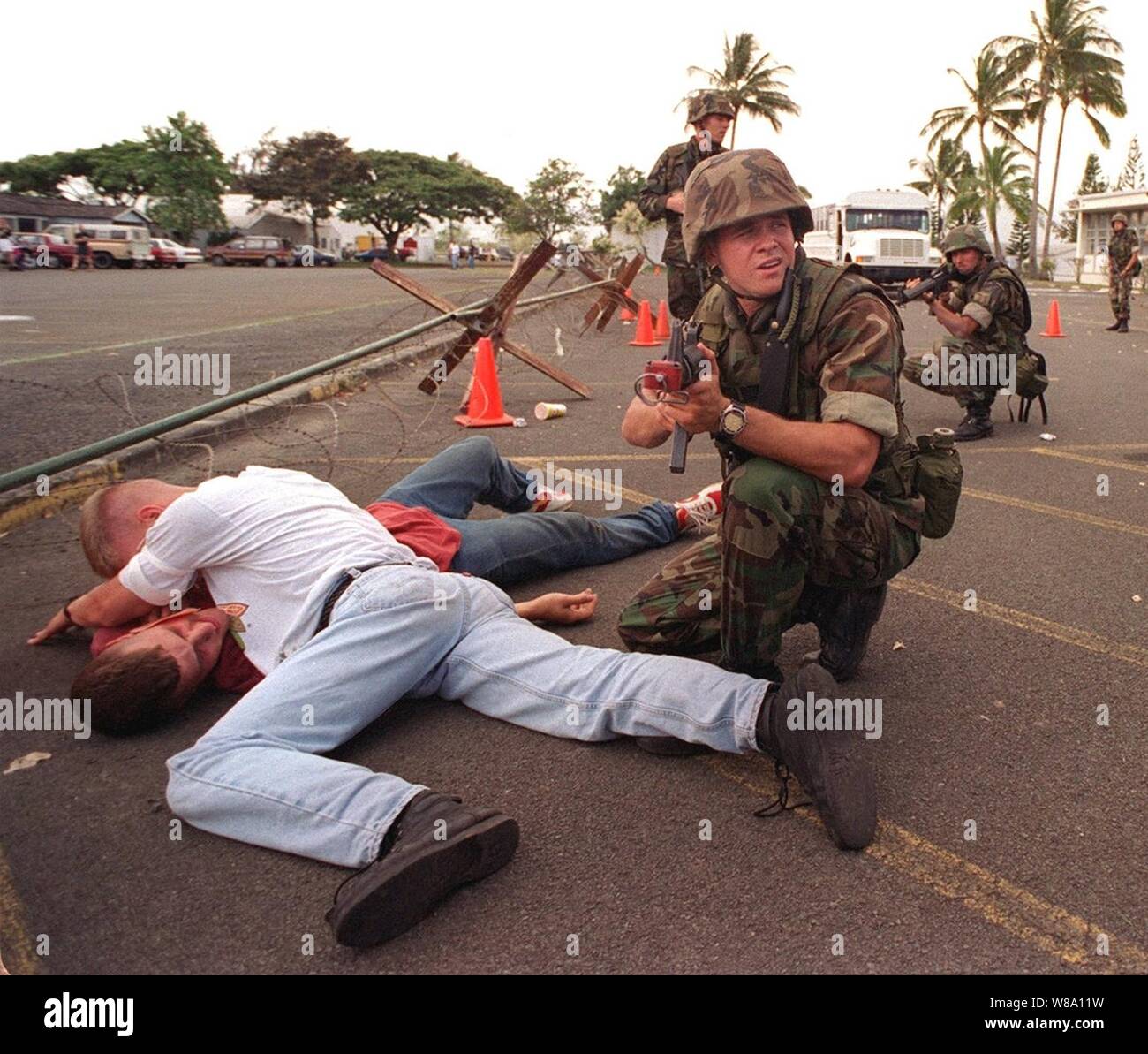 Navy Hospital Corpsman Eric Carver watches over two ТwoundedУ civilians seeking asylum in a fictitious American embassy while being fired upon during a simulated Noncombatant Evacuation Operation on June 11, 1996, at Kaneohe Bay Marine Corps Station, Hawaii, as part of exercise RIMPAC Ф96.  More than 44 ships, 200 aircraft and 30,000 soldiers, sailors, Marines, airmen and Coast Guardsmen are involved in the exercise.  The purpose of RIMPAC Ф96 is to improve coordination and interoperability of combined and joint forces in maritime tactical and theater operations.  Australia, Canada, Chile, Jap Stock Photo