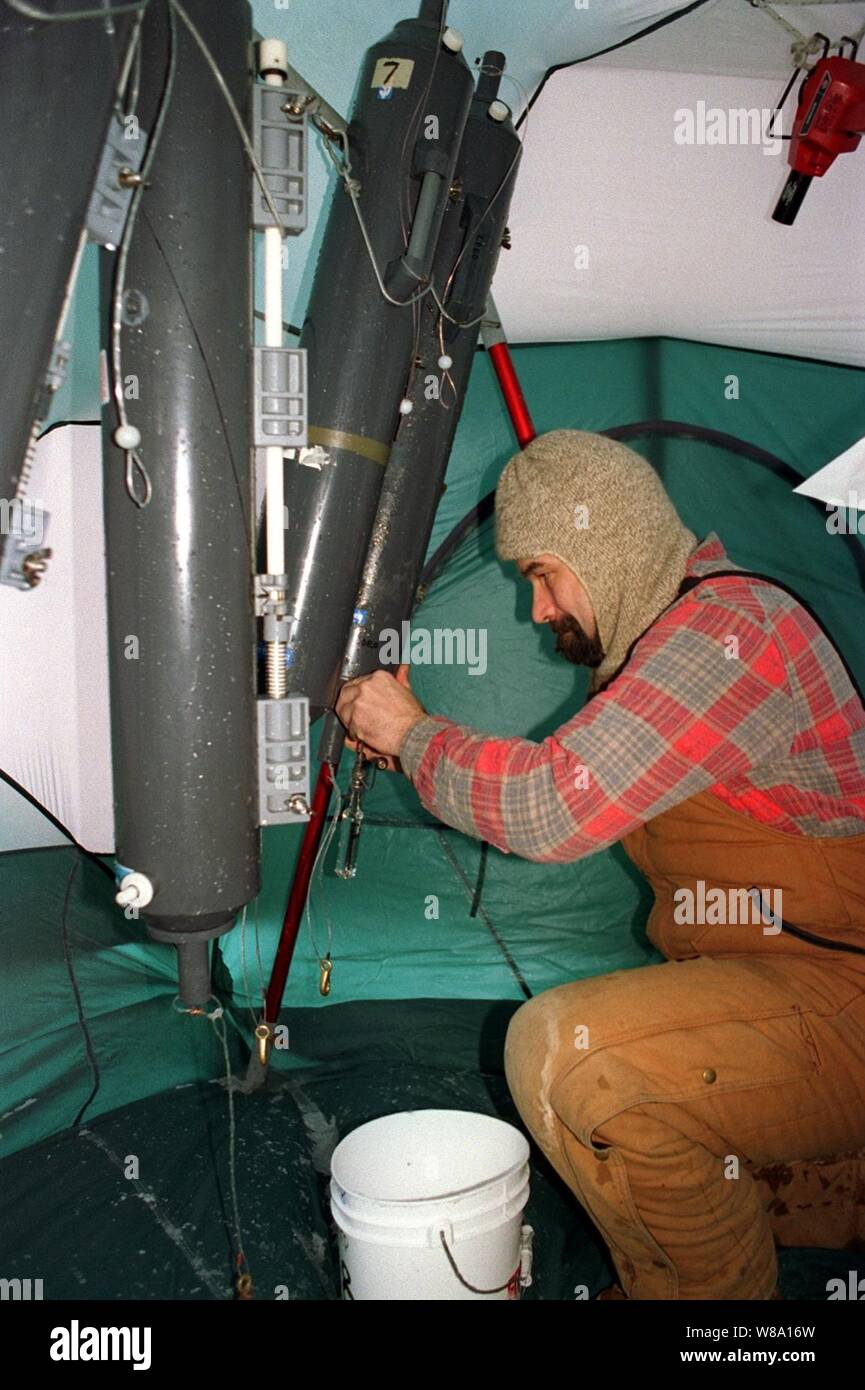 Columbia University scientist Jay Ardie works to decant deep water samples from Nisken bottles hanging in a temporary enclosure on the deck of the attack submarine USS Pogy (SSN 647).  The submarine is on a 45-day research mission to the North Pole.  Seven scientists and technical advisors are conducting experiments and collecting samples for studies in water mass properties, geophysics, ice mechanics and pollution detection in the Arctic Ocean.  The research voyage is the second of five planned deployments through the year 2000. Stock Photo