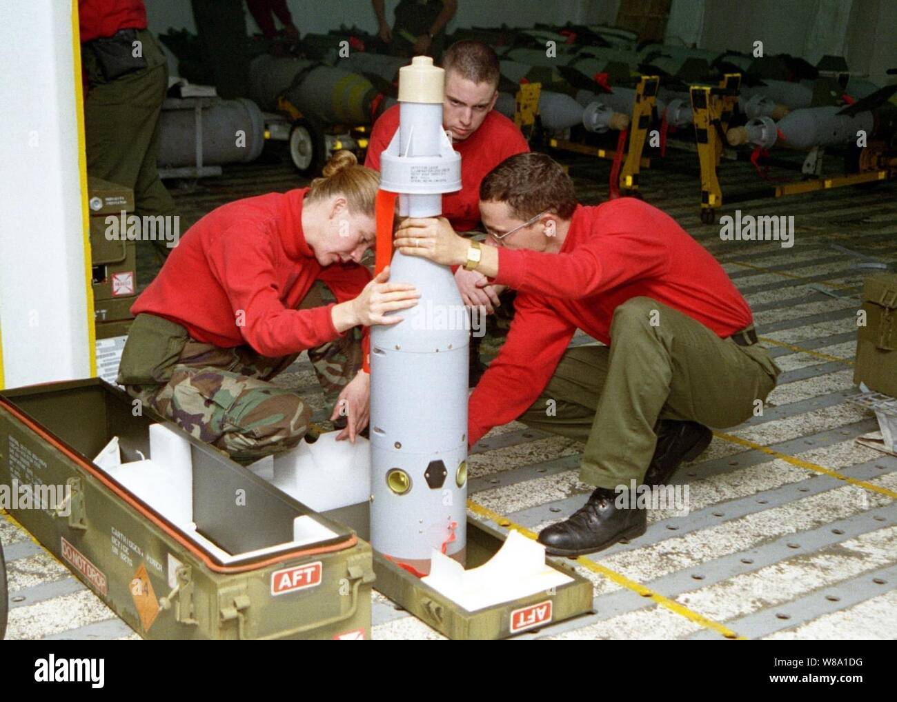 Petty Officer 2nd Class Kathy Higingbotham (left) Airman Apprentice Jon Mitchell (center) and Aviation Ordnanceman Thomas Moore (right) inspect the guidance system assembly on a laser guided GBU-16 bomb on board the aircraft carrier USS Nimitz (CVN 68) on Nov. 10, 1997.  The USS Nimitz (CVN 68) battle group is operating in the Persian Gulf in support of the U.S. and coalition enforcement of the no-fly-zone over Southern Iraq. All three are aviation ordnancemen assigned to the weapons department aboard the USS Nimitz. Higingbotham is from Addy, Wash.;  Mitchell is from Lakeland, Fla.; and Moore Stock Photo