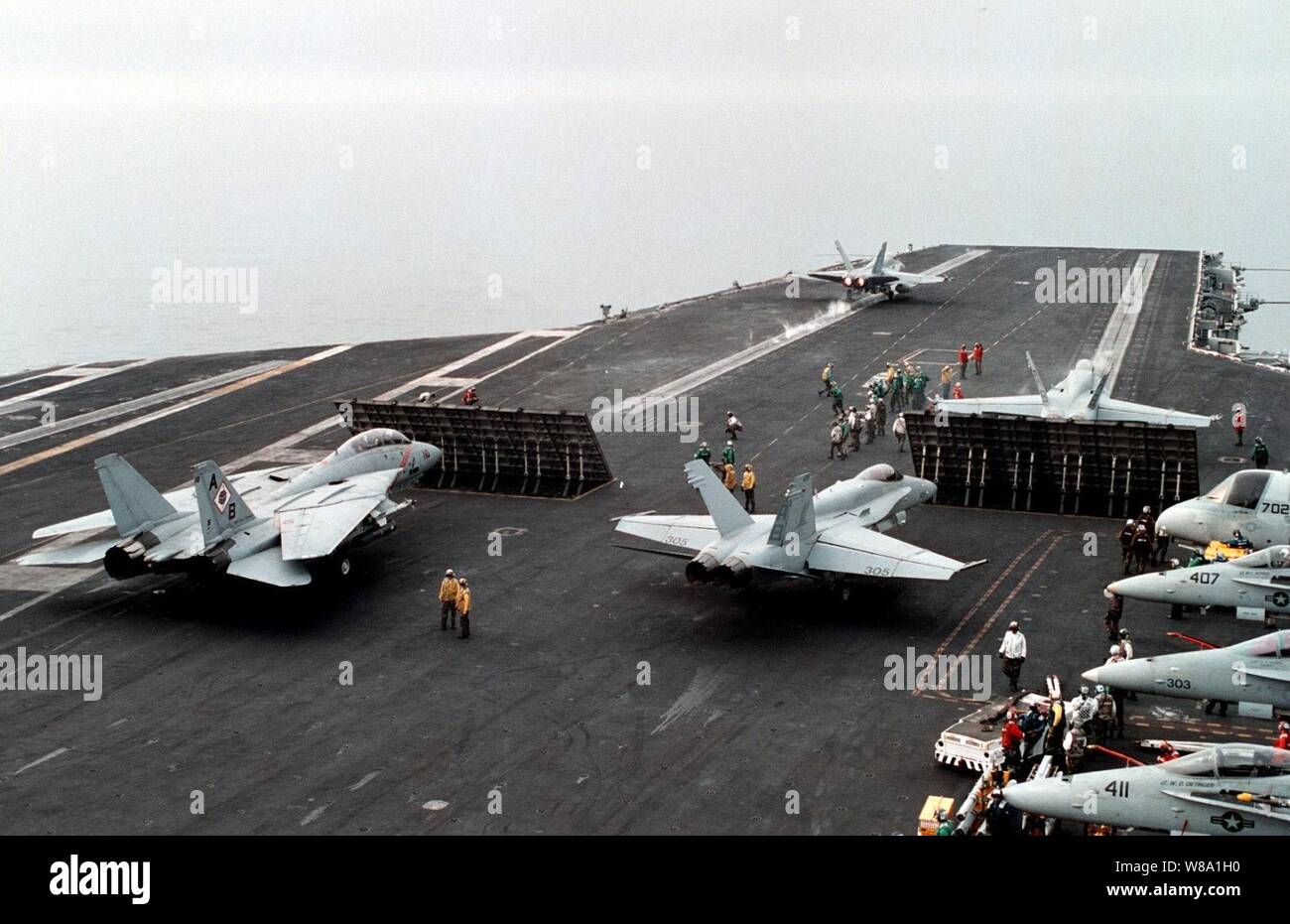 An F/A-18 Hornet hurtles down the No. 2 catapult while an F-14 Tomcat (left) and other Hornets line up for the next launch cycle on the USS George Washington (CVN 73) as the ship steams in the Persian Gulf on Feb. 7, 1998.  The Washington battle group is operating in the Persian Gulf in support of Operation Southern Watch which is the U.S. and coalition enforcement of the no-fly-zone over Southern Iraq. Stock Photo