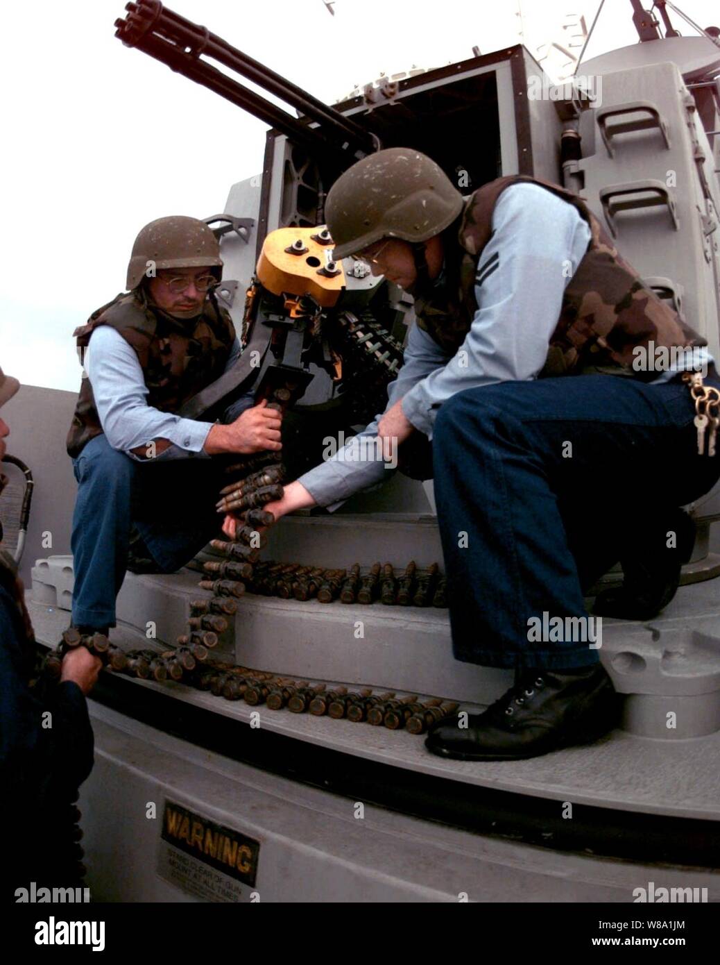 Petty Officers 2nd Class Miguel Villarreal (left) and Tracy Anderson (right) load a chain of 20 mm ammunition into the forward Phalanx Close-in Weapon System mount aboard the guided missile destroyer USS John S. McCain (DDG 56) on Feb. 11, 1998.  The McCain is operating in the Persian Gulf in support of Operation Southern Watch which is the U.S. and coalition enforcement of the no-fly-zone over Southern Iraq.  Villarreal and Anderson are Navy fire controlman. Stock Photo