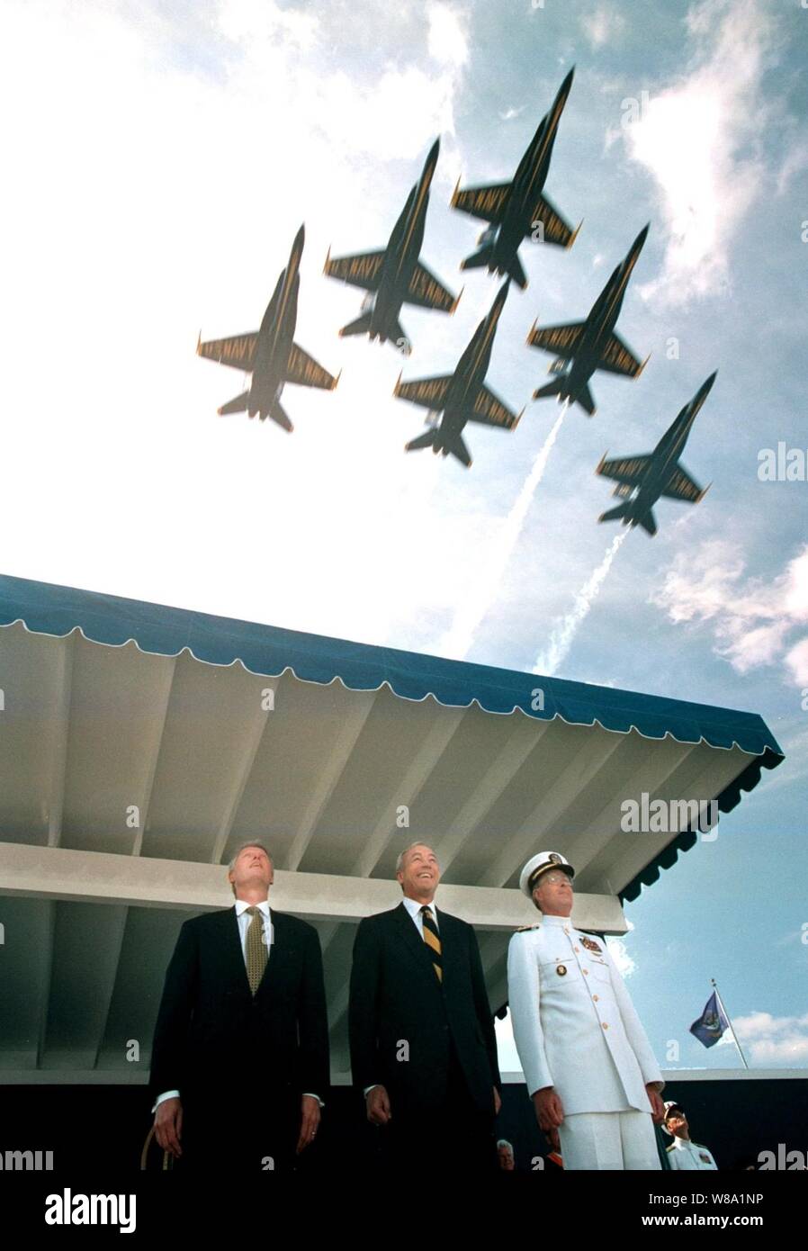 President William J. Clinton (left), Secretary of the Navy John H. Dalton (center) and Academy Superintendent Admiral Charles R. Larson, U.S. Navy, look skyward as the Navy Blue Angels fly over the Naval Academy stadium on May 22, 1998, to kick off the graduation and commissioning ceremonies for the U.S. Naval Academy class of 1998. Stock Photo