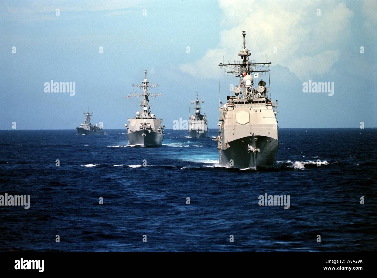 The Ticonderoga Class Guided Missile Cruiser USS Vincennes (CG 49) (right) steams in front of three other classes of U.S. Navy ships as they operate in the Pacific Ocean during a Y2K operational testing exercise on Sept. 18, 1999.  Following the Vincennes from right to left are the Spruance Class Destroyer USS John Cushing (DD 985), Arleigh Burke Class Guided Missile Destroyer USS John S. McCain (DDG 56), and the Oliver Hazard Perry class Guided Missile Frigate USS Gary (FFG 51). Stock Photo