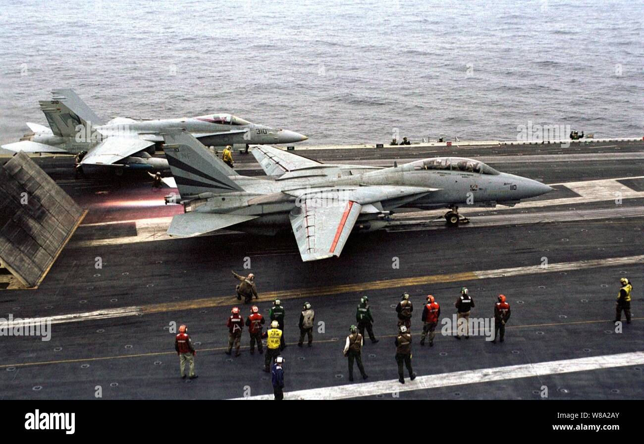 Flight deck personnel watch as an F-14 Tomcat hits the afterburner before launching from the aircraft carrier USS Kitty Hawk (CV 63) during Exercise Foal Eagle '99 on Oct. 31, 1999.  The Kitty Hawk (CV 63) and its embarked Carrier Air Wing 5 are participating in Exercise Foal Eagle Ф99. which is the 38th in a series of regularly scheduled rear area defense field training exercises.  The annual exercise is held at a variety of locations throughout the Korean peninsula and involves some 30,000 U.S. military forces.  The Tomcat is attached to Fighter Squadron 154. Stock Photo