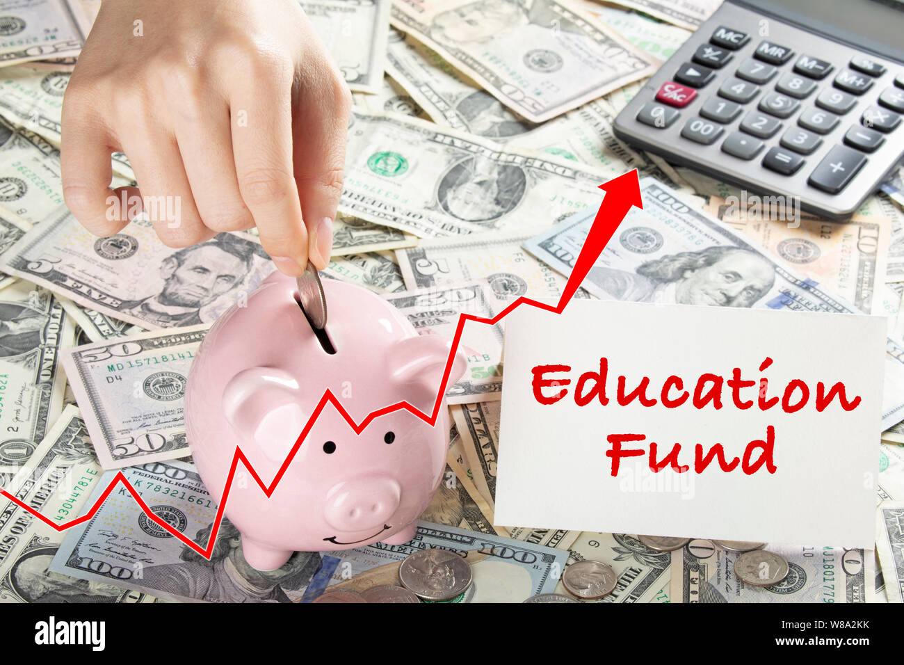 United States bank notes and coins with a calcultor, piggy bank, and hand placing coin into piggy bank and a card that says education fund Stock Photo