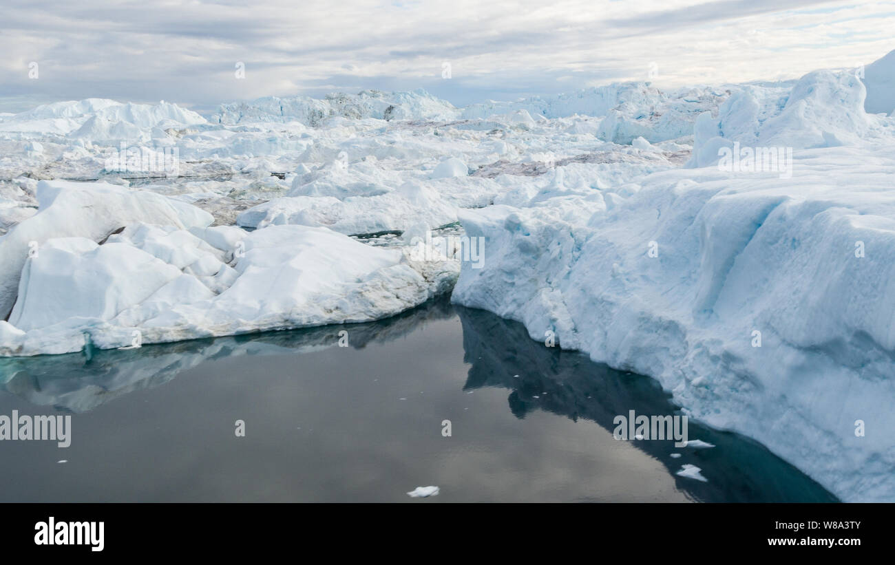 Global Warming and Climate Change - Icebergs and ice from melting glacier in icefjord in Ilulissat, Greenland. Aerial image of arctic nature ice landscape. Unesco World Heritage Site. Stock Photo