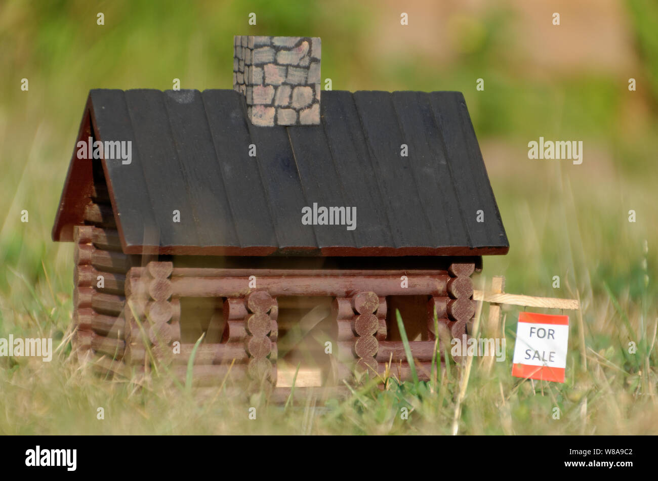 A miniature house with a for sale sign illustrates the concepts of real estate, housing market, tiny homes Stock Photo