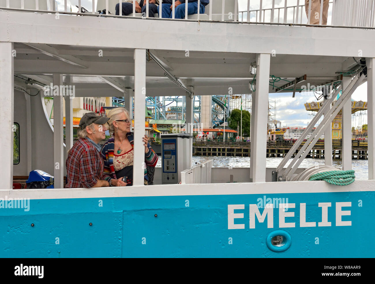 Authentic middle aged couple enjoy the sights aboard tour boat ferry Emelie, Lake Malaren, Stockholm, Sweden.Tivoli Gröna Lund amusement park behind. Stock Photo