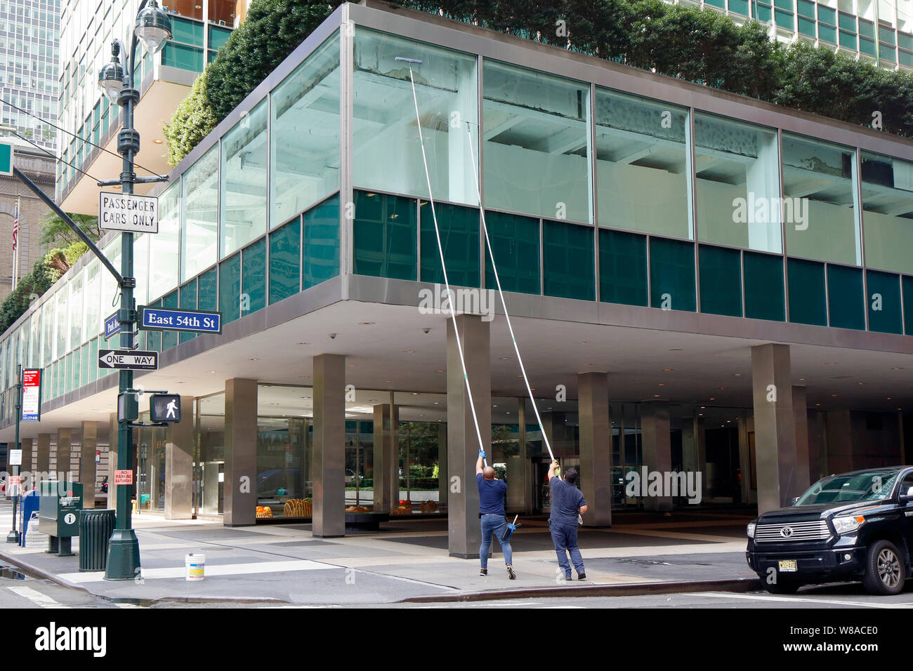 Window washers with extremely long poles clean a window on Park Ave in