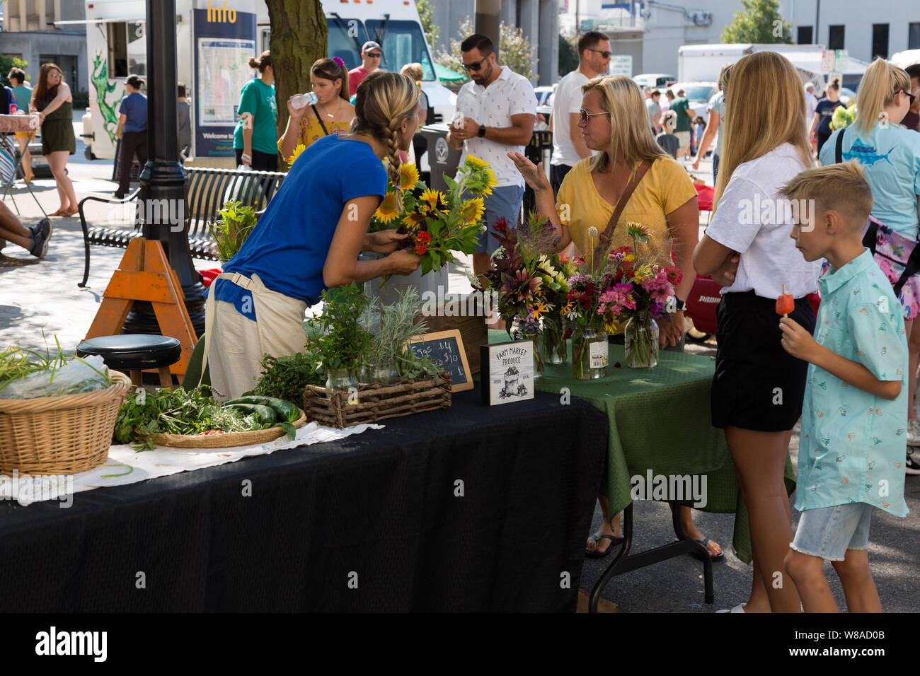 A flower vendor at Fort Wayne's Farmers' Market promotes her flowers to potential customers in downtown Fort Wayne, Indiana, USA. Stock Photo