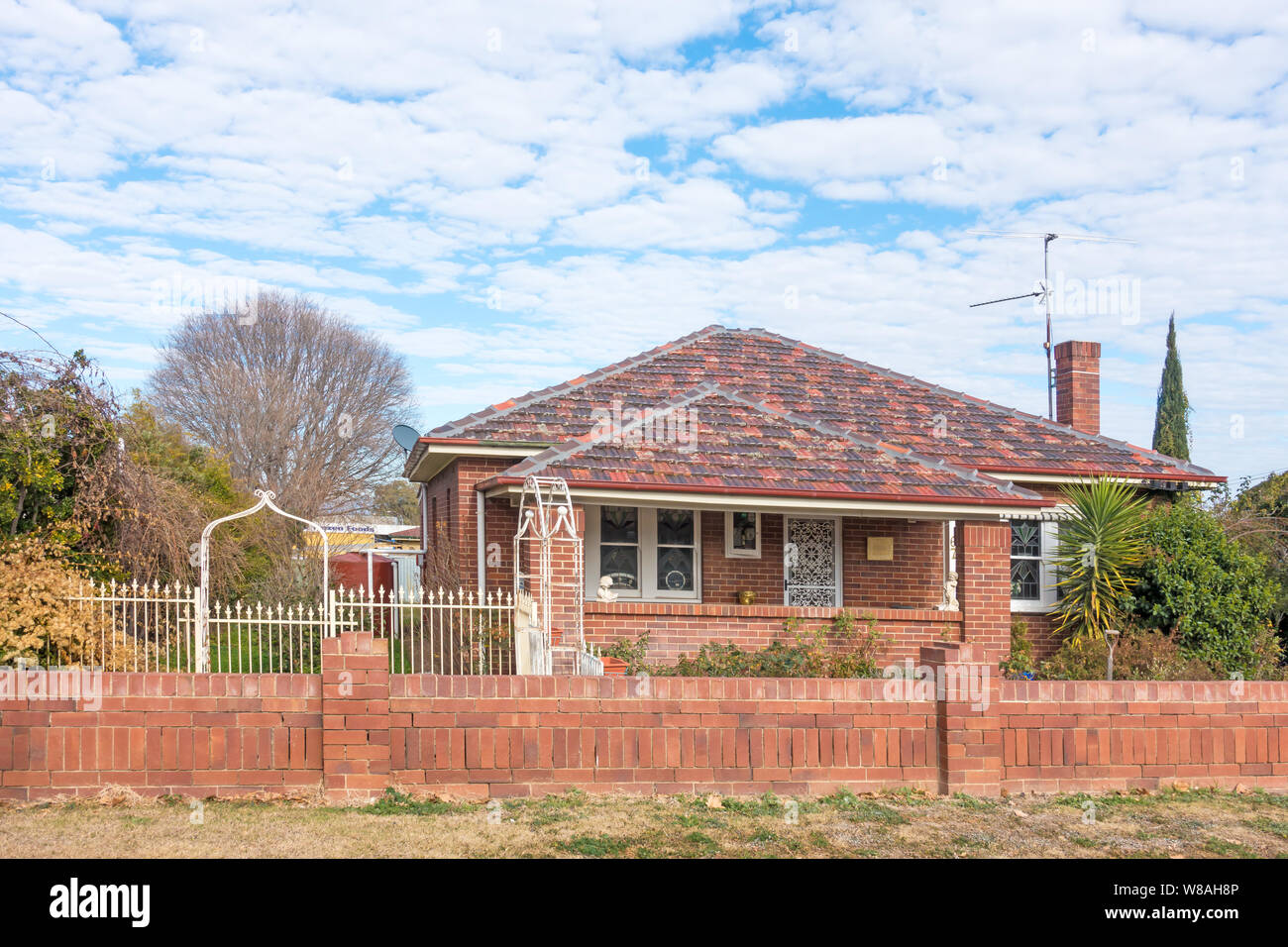 1920s brick bungalow with terracotta tile roof and brick wall front fence. Tamworth Australia. Stock Photo
