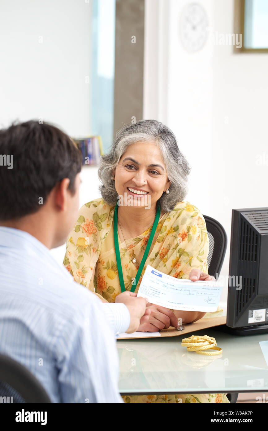 Bank manager giving cheque to her customer as gold loan Stock Photo - Alamy