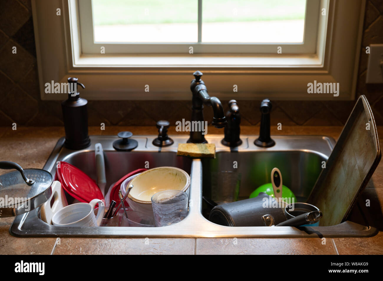Stack of dirty dishes piled into the kitchen sink Stock Photo