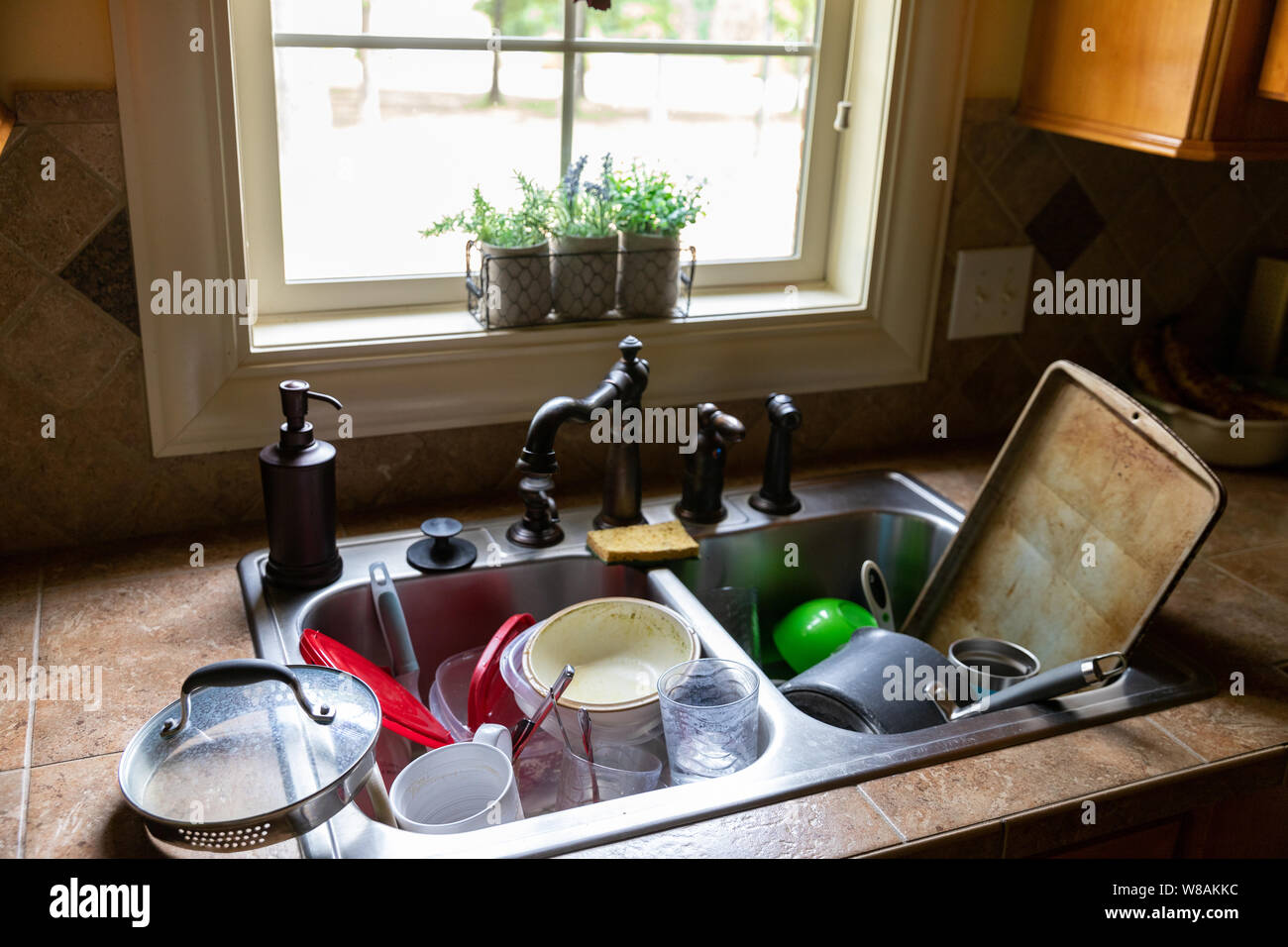 Stack of dirty dishes piled into the kitchen sink Stock Photo
