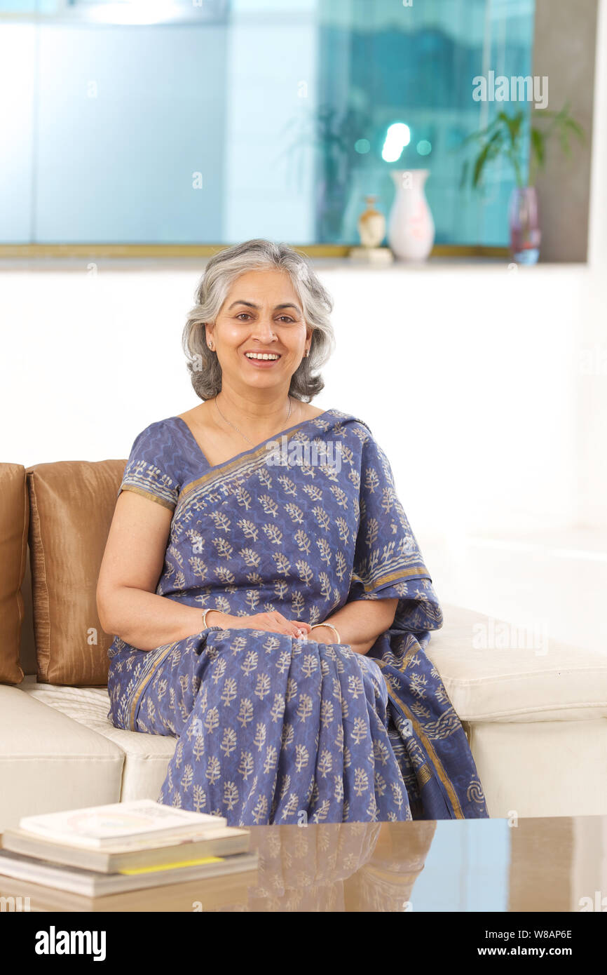 Senior woman sitting on a couch and smiling Stock Photo - Alamy