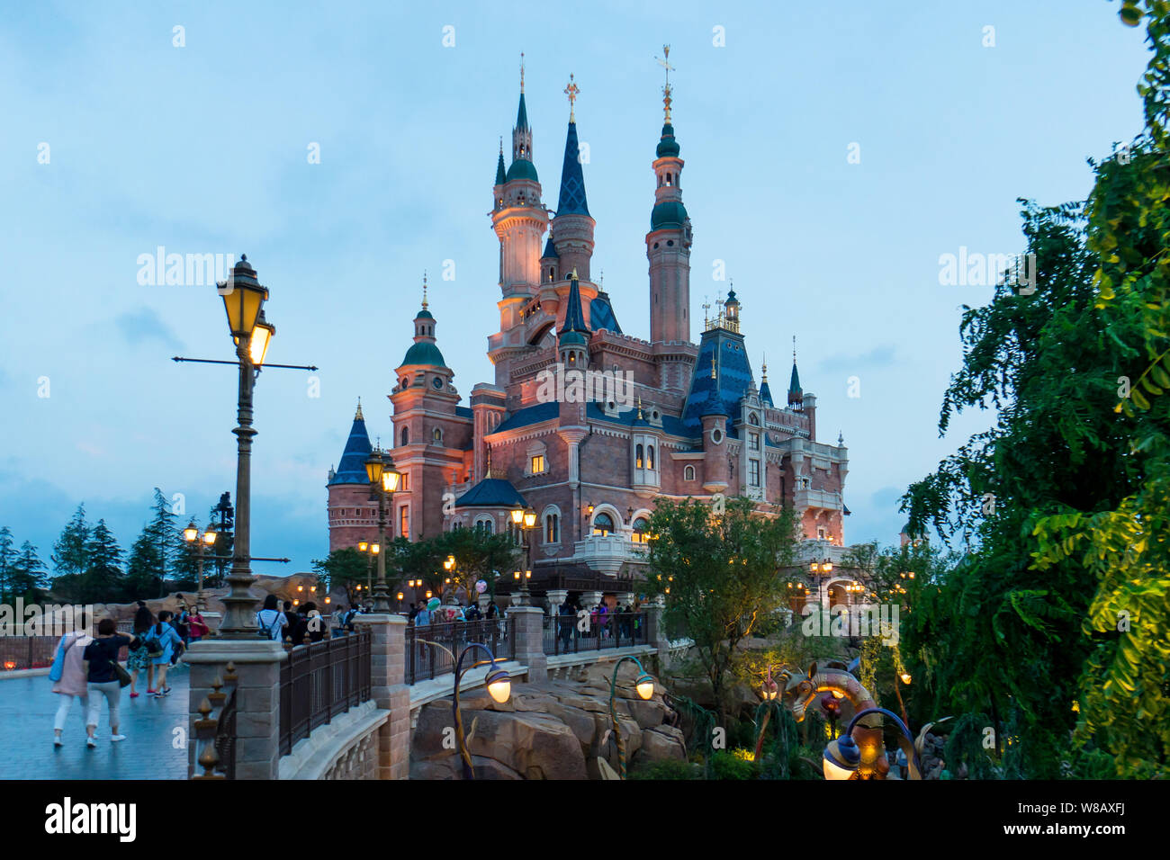 Tourists visit the illuminated Disney Castle in the Shanghai Disneyland during the trial operation at the Shanghai Disney Resort in Pudong, Shanghai, Stock Photo