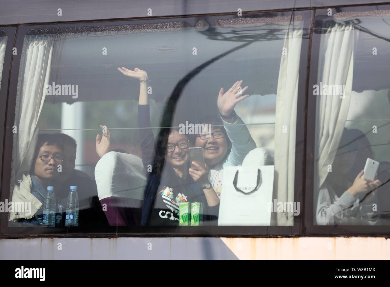 Chinese students of Maotanchang High School wave to a crowd of people from a bus as they are on their way to take the national college entrance exam, Stock Photo