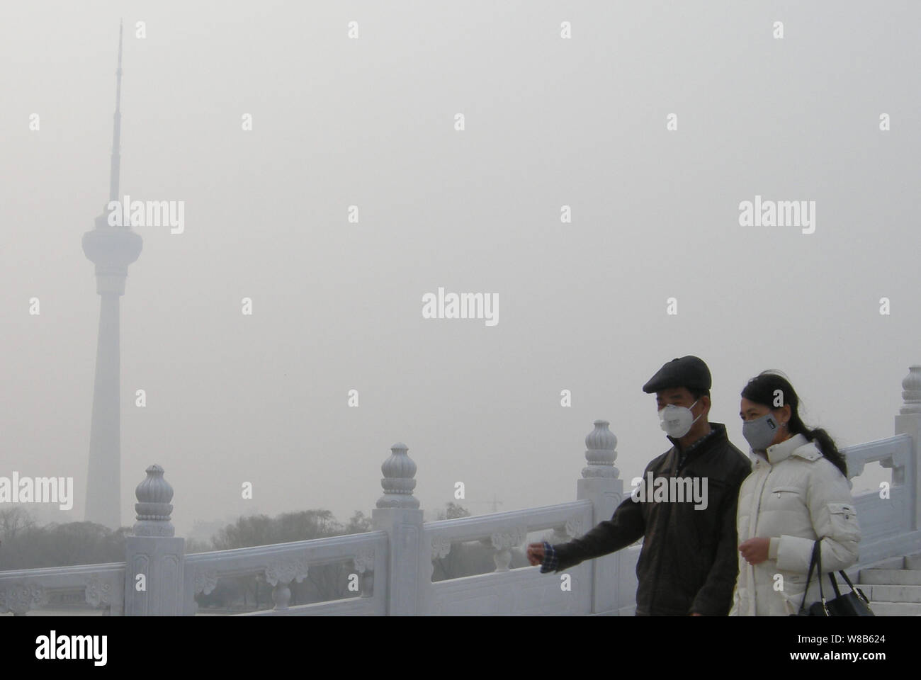 --FILE--Pedestrians wearing face masks walk on a road in heavy smog in Beijing, China, 16 March 2016.   Beijing municipal authorities are mulling whet Stock Photo
