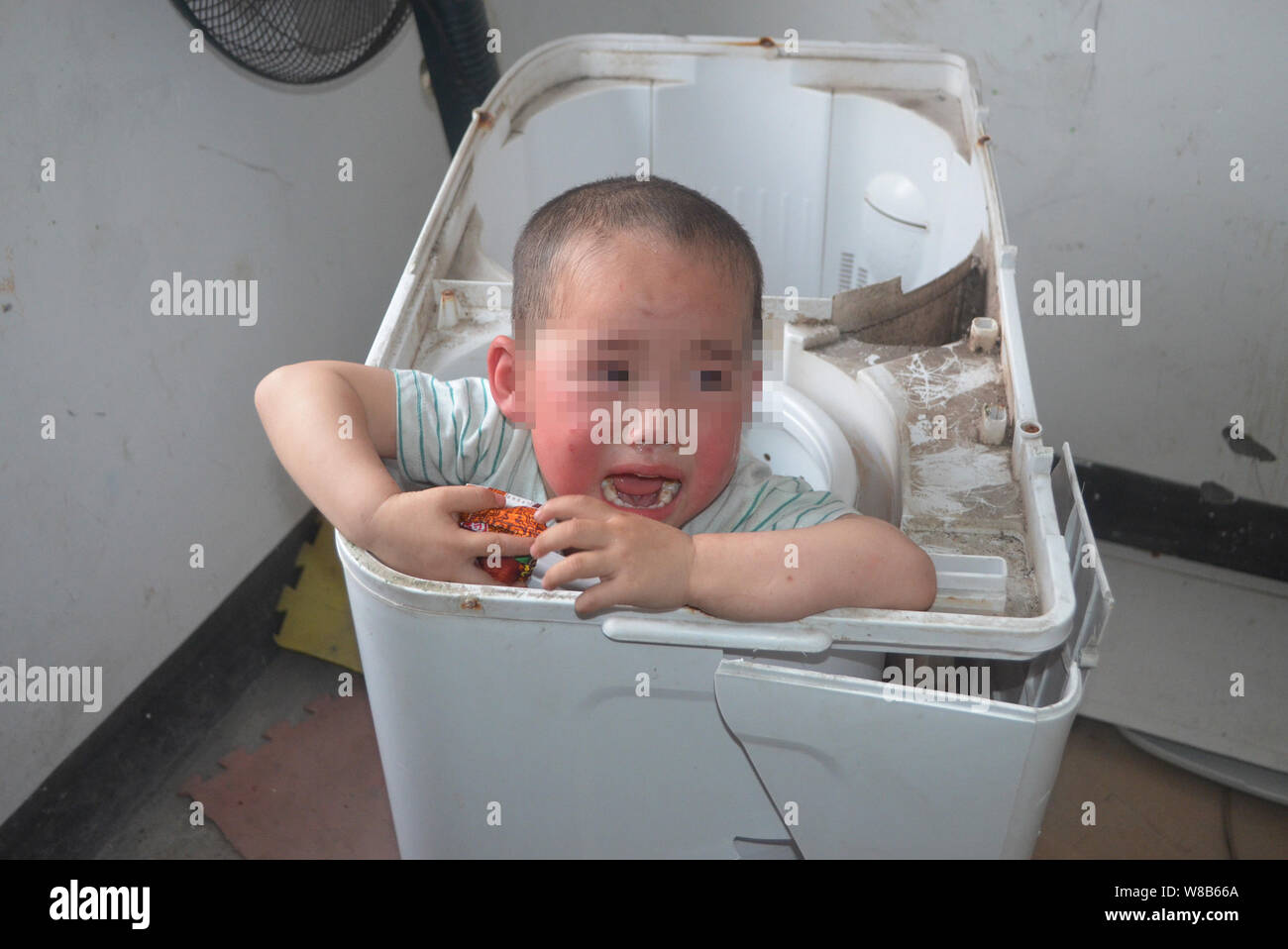 The boy stuck in a washing machine cries while firefighters are dismantling the machine to rescue him at home in Lingjia town, Neijiang city, southwes Stock Photo