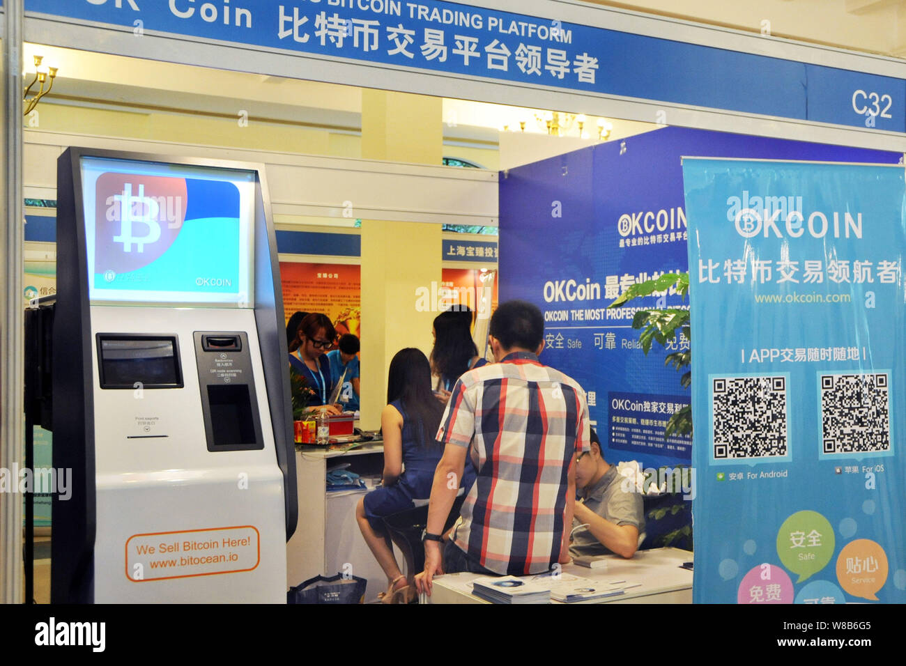 FILE--Employees work next to a Bitcoin ATM at the stand of Bitcoin trading  platform okcoin.com during an expo in Shanghai, China, 27 June 2014. The  Stock Photo - Alamy