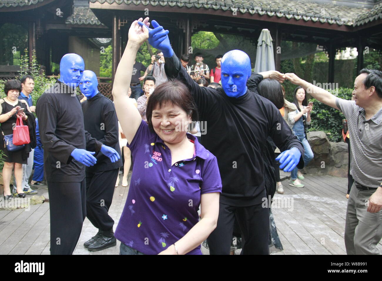 Performers from the Blue Man Group dance with visitors near the Broken Bridge on the West Lake during a flash mob event in Hangzhou city, east China's Stock Photo