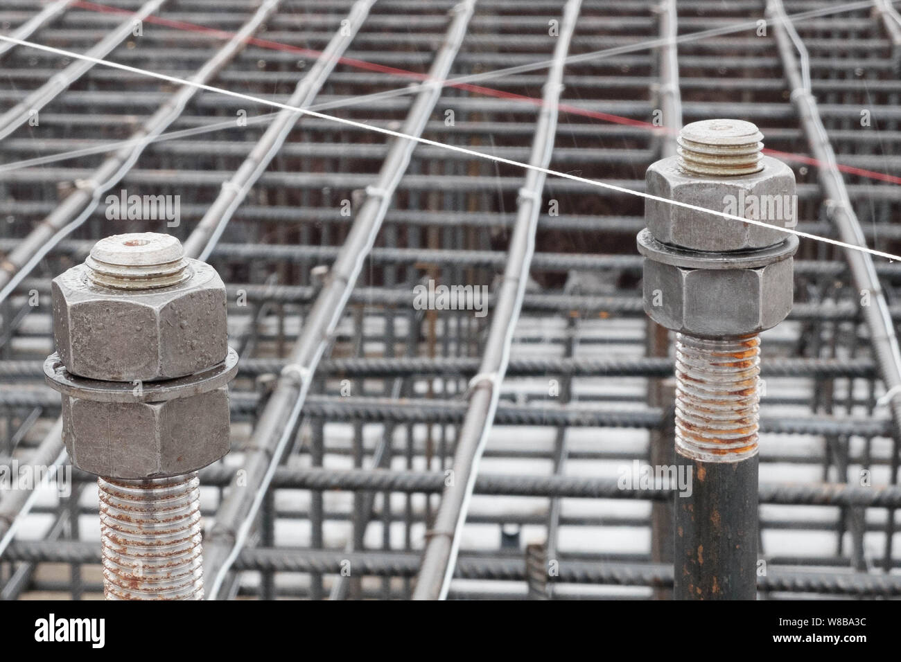 Two steel anchor bolts with screw nuts and steel grid on tower crane ...