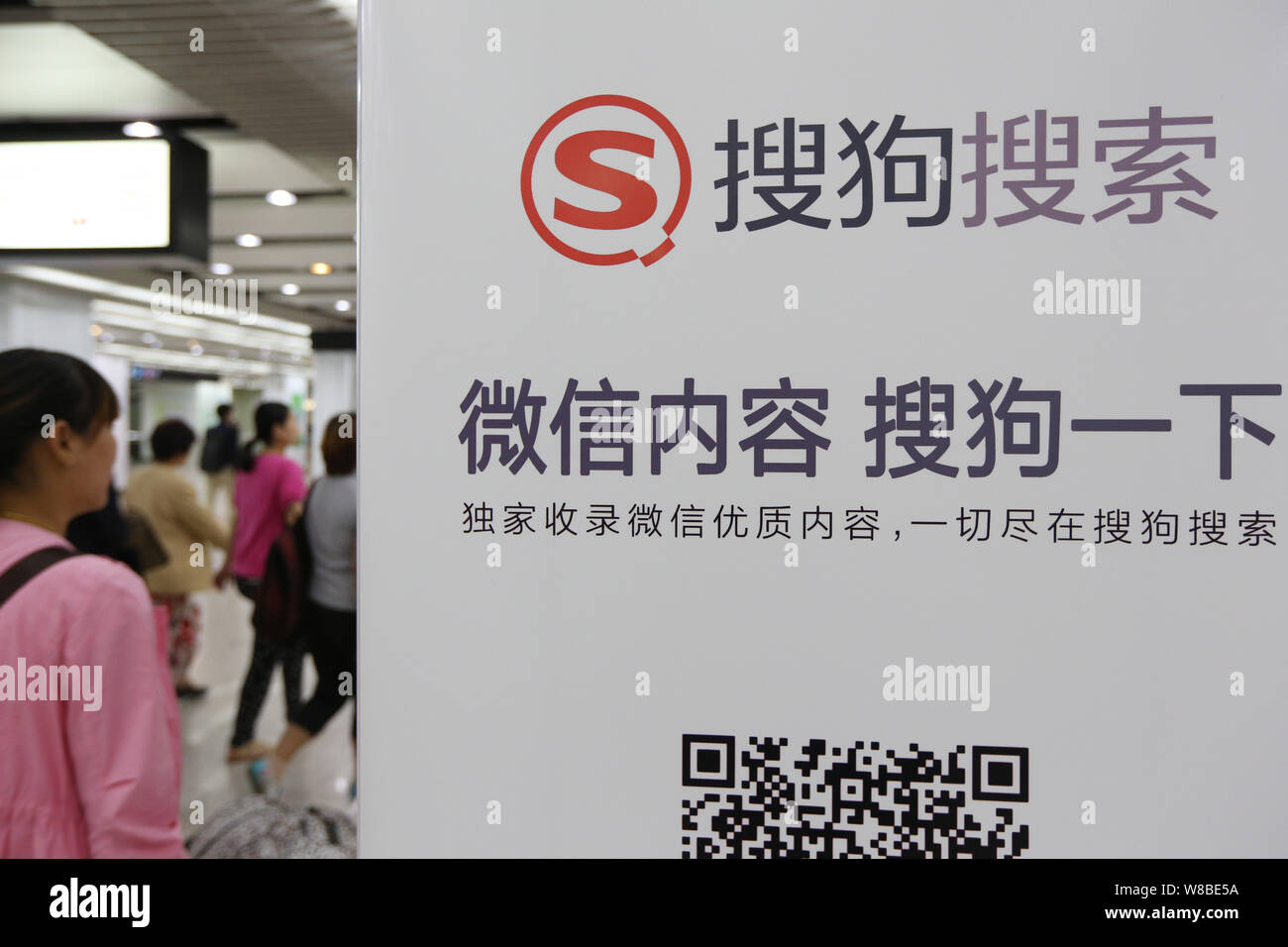 --FILE--Pedestrians walk past an advertisement for Sogou search engine at a metro station in Shanghai, China, 12 September 2014.   Sogou Inc joined fo Stock Photo