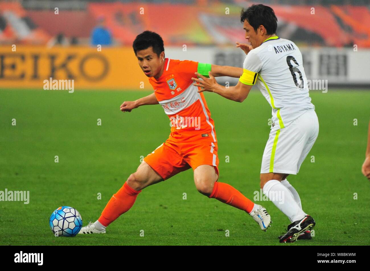 Hao Junmin of China's Shandong Luneng, left, challenges Toshihiro Aoyama of Japan's Sanfrecce Hiroshima in their Group F match during the 2016 AFC Cha Stock Photo