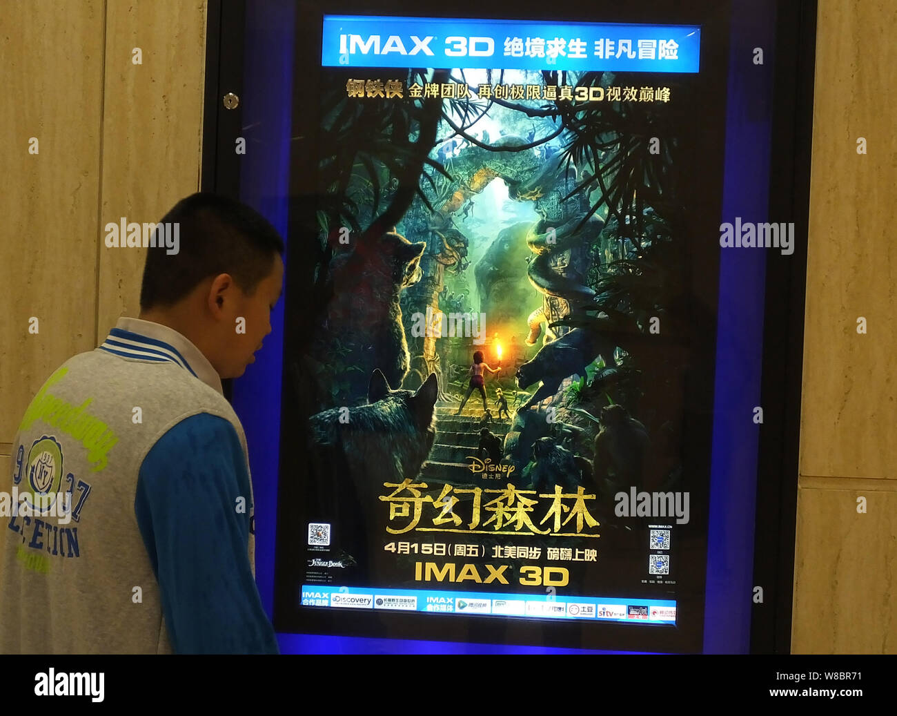 A Chinese filmgoer looks at a poster of the movie 'The Jungle Book' at a cinema in Yichang city, central China's Hubei province, 14 April 2016.   Jon Stock Photo