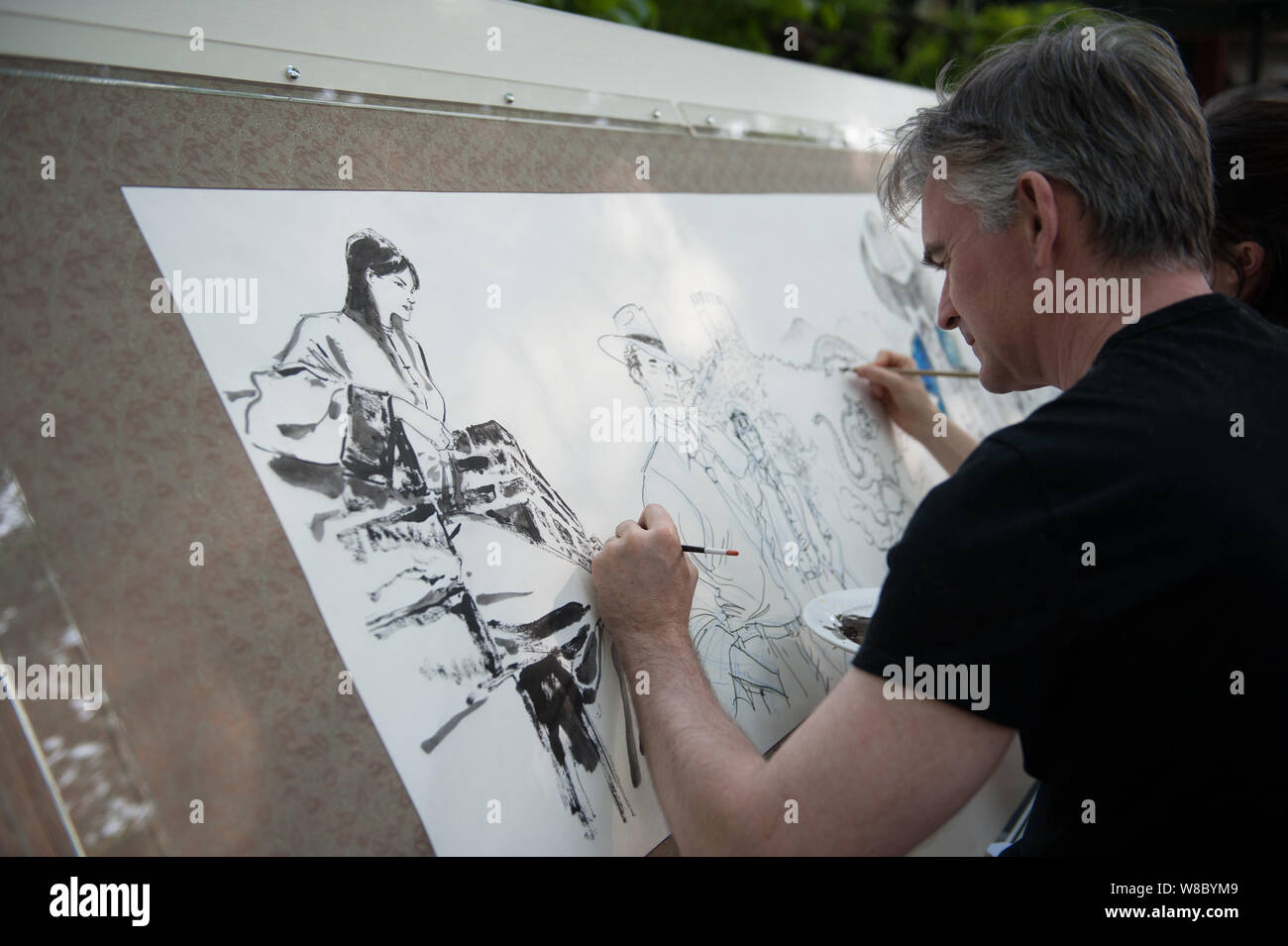 A foreign cartoonist draws pictures showing their impressions of Beijing during the "Drawing Beijing - World Artists Illustrate Beijing" event at Shic Stock Photo