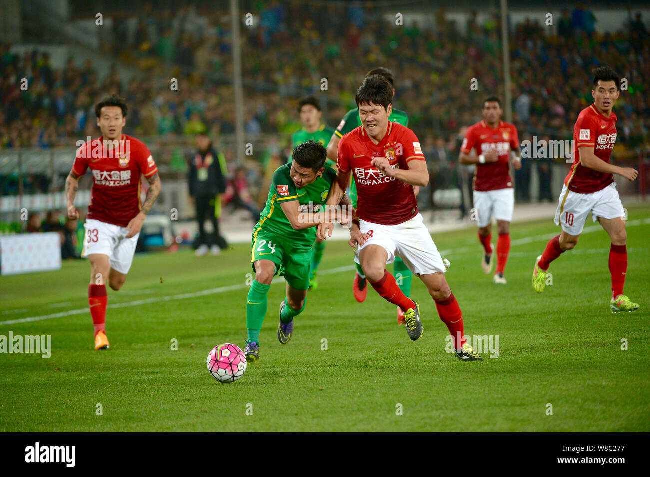 Kim Young-gwon of Guangzhou Evergrande, center right, challenges Li Hanbo of Beijing Guoan in their fourth round match of the 2016 Chinese Football As Stock Photo