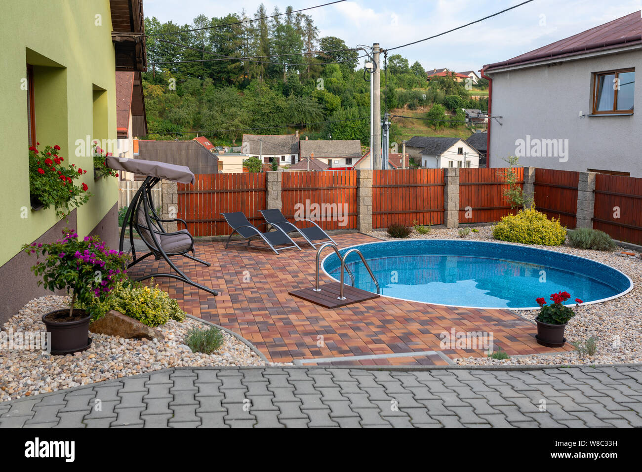 small home swimming pool with two black sun loungers and rocking bench Stock Photo Alamy