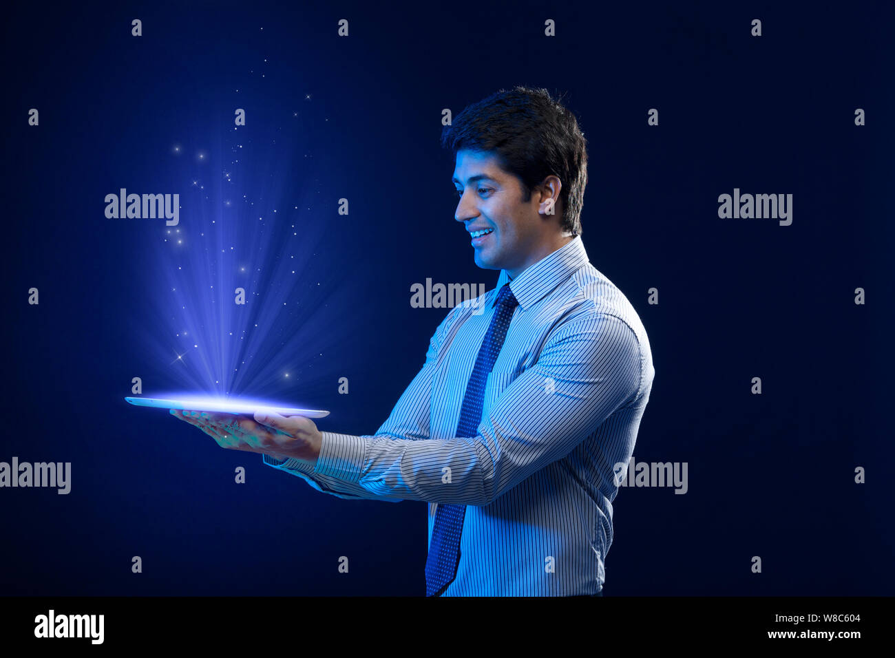 Businessman looking at lights coming from digital tablet Stock Photo