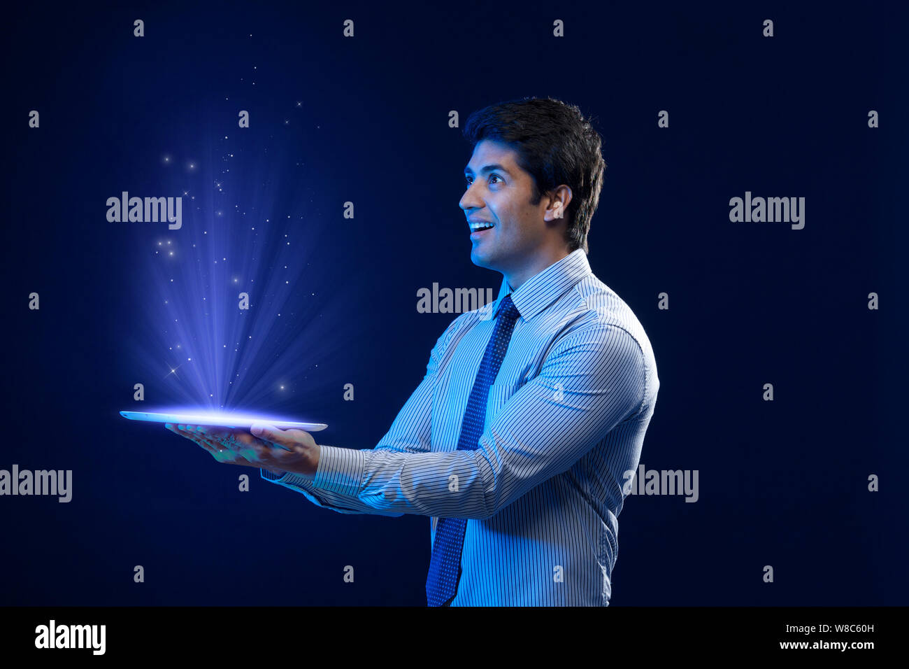 Businessman looking at lights coming from digital tablet Stock Photo