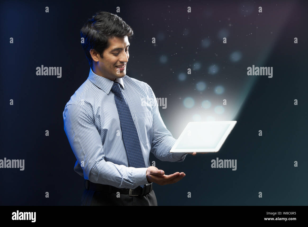 Businessman looking at lights coming from digital tablet Stock Photo