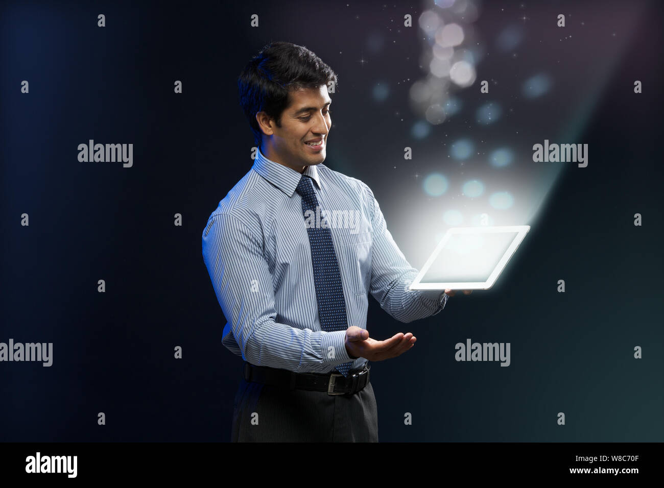 Businessman looking at lights coming from digital tablet Stock Photo
