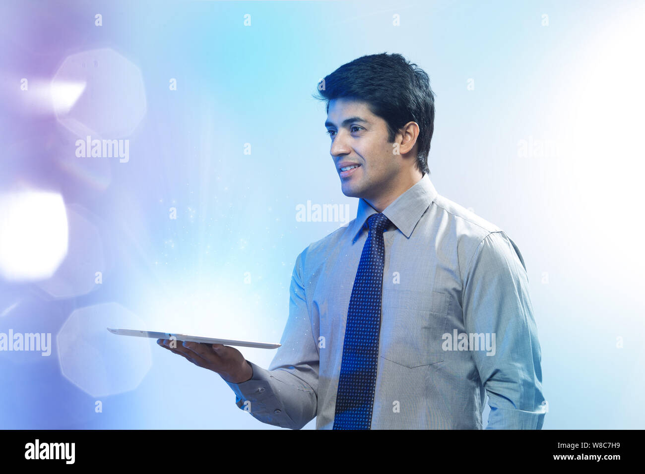 Businessman looking at lights coming from digital tablet Stock Photo
