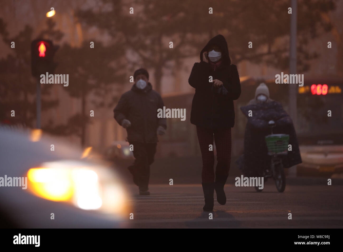 Pedestrians wearing face masks walk across a road in heavy smog in Beijing, China, 22 December 2015.   Air pollution in Beijing worsened even as envir Stock Photo