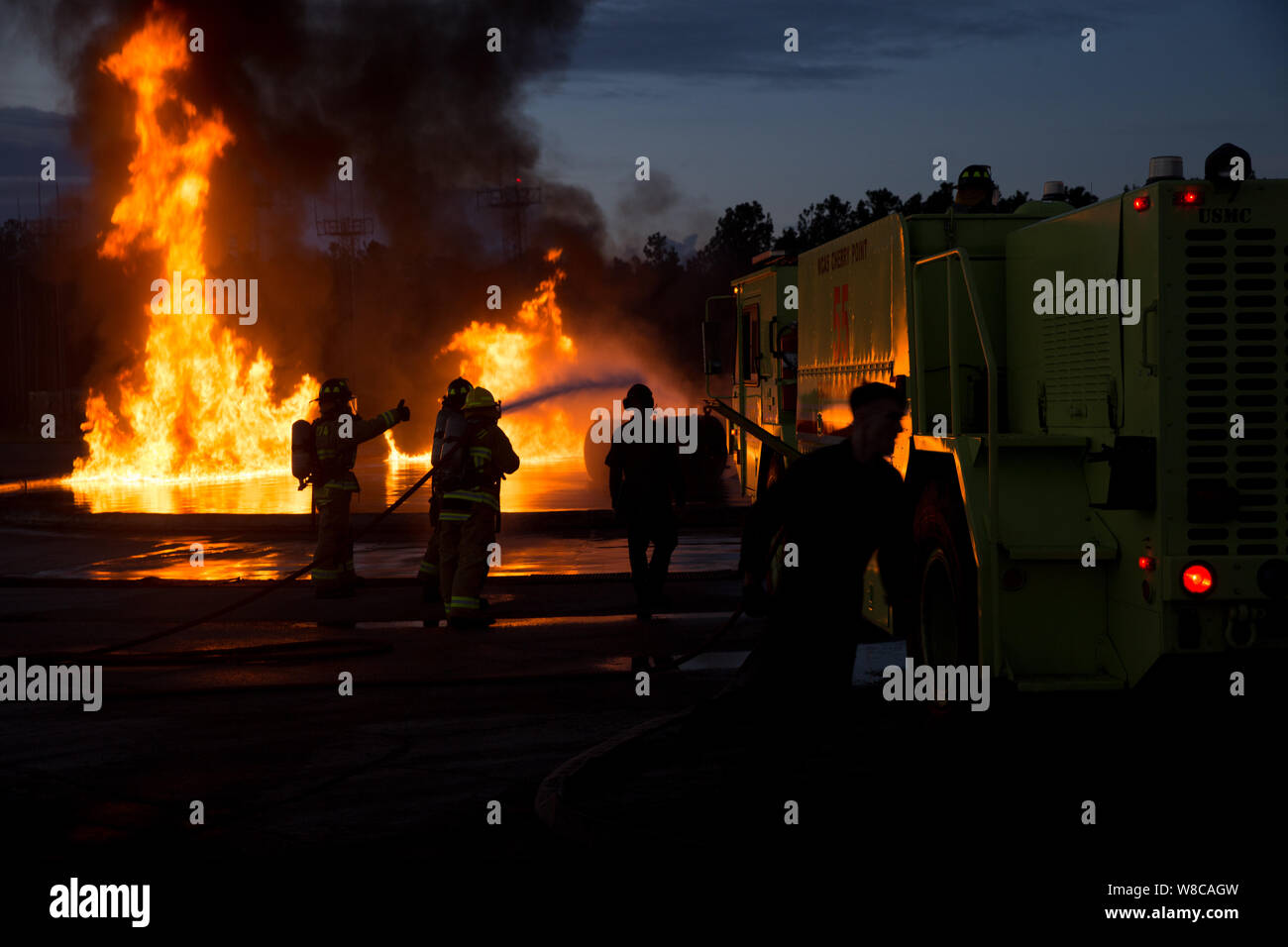 U.S. Marines with Aircraft Rescue and Firefighting (ARFF) assigned to Headquarters and Headquarters Squadron, conduct a controlled fuel burn drill at Marine Corps Air Station Cherry Point, North Carolina, July 31, 2019. The training exercise replicated the kind of fires they may encounter in the line of duty and helped familiarize the Marines with the vehicles, gear, and rescue equipment needed to safely and efficiently extinguish fuel fires. The ARFF Marines used hand-line attacks as well as P-19 fire trucks to contain the flames. (U.S. Marine Corps photo by Lance Cpl. Michael Neuenhoff). Stock Photo
