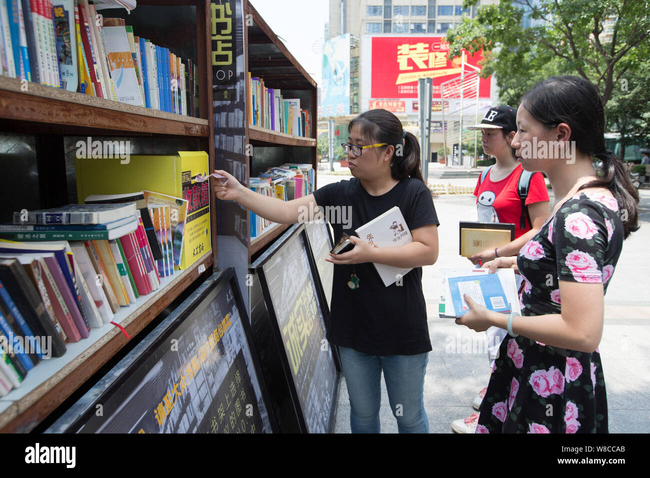 A woman drops money into a lock-box for books she purchased at the staffless Honesty Bookstore in Xinjiekou Street, Nanjing city, east China's Jiangsu Stock Photo