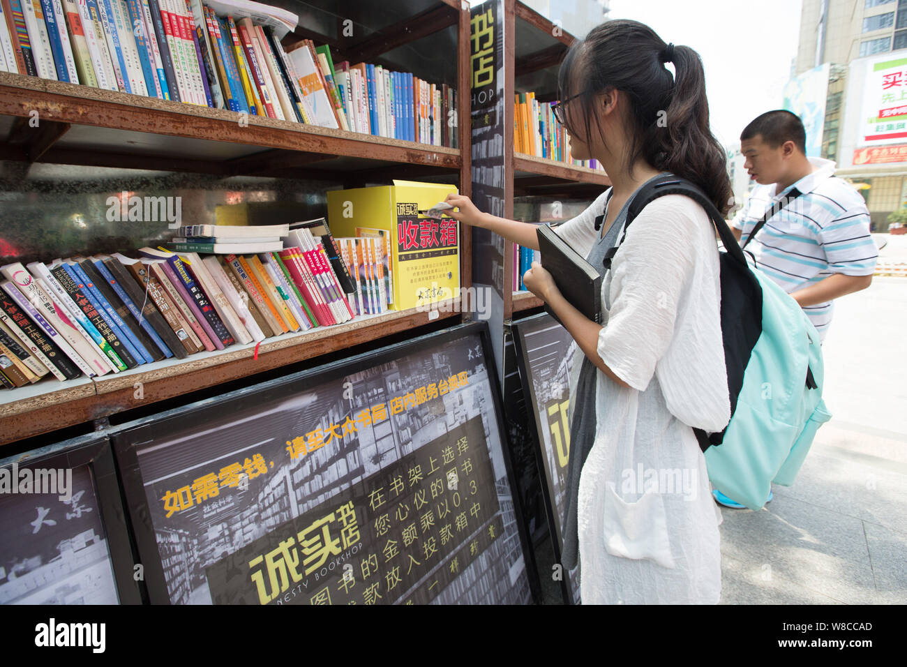 A girl drops money into a lock-box for books she purchased at the staffless Honesty Bookstore in Xinjiekou Street, Nanjing city, east China's Jiangsu Stock Photo