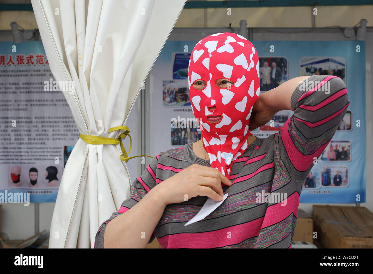 Chinese facekini designer Zhang Shifan puts on a facekini mask at her stand during the 13th China International Marine Fair and China (Qingdao) Intern Stock Photo