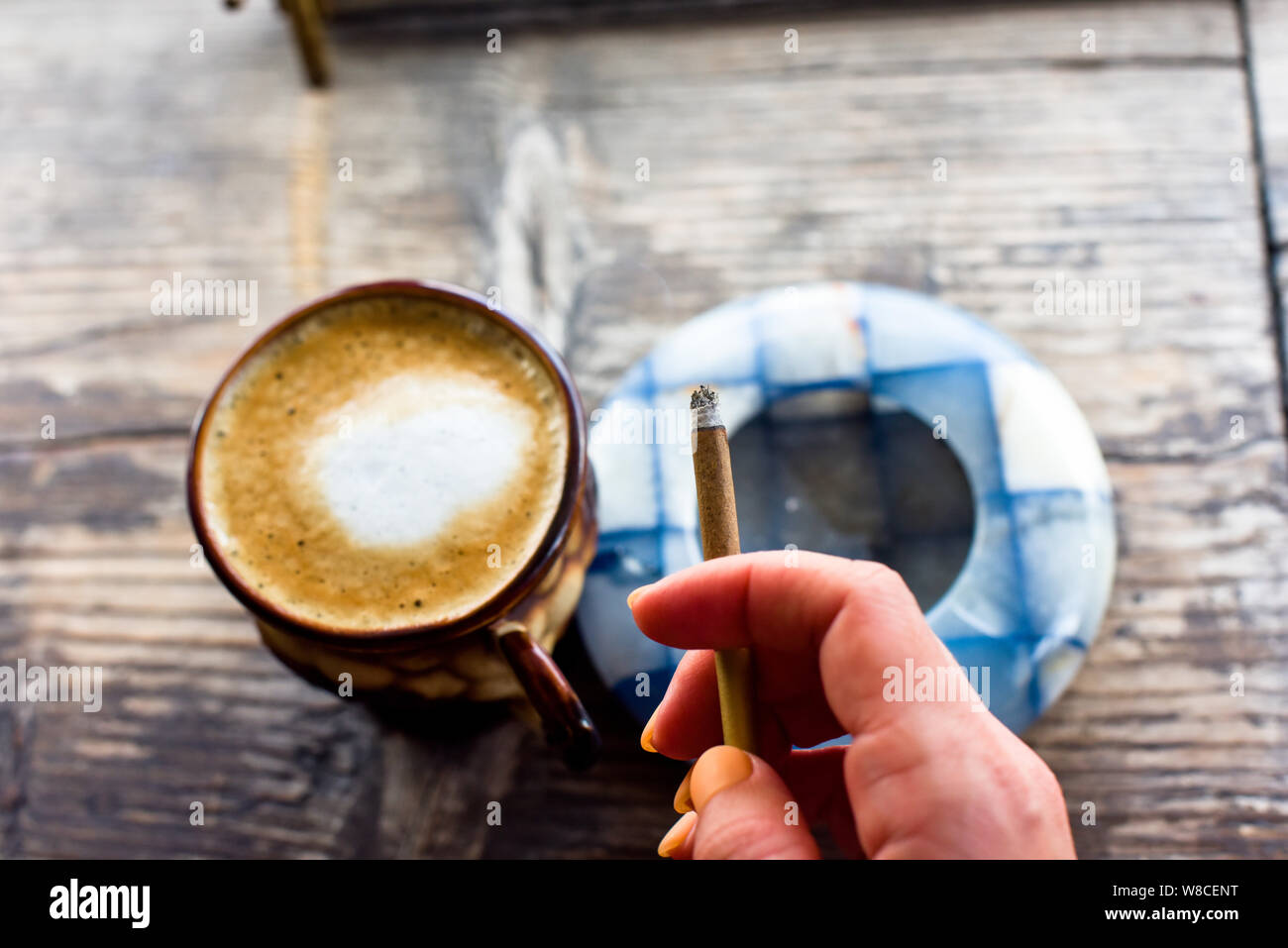 Coffee cigarette on the table. Cigarette in a woman's hand with a beautiful manicure. Blue