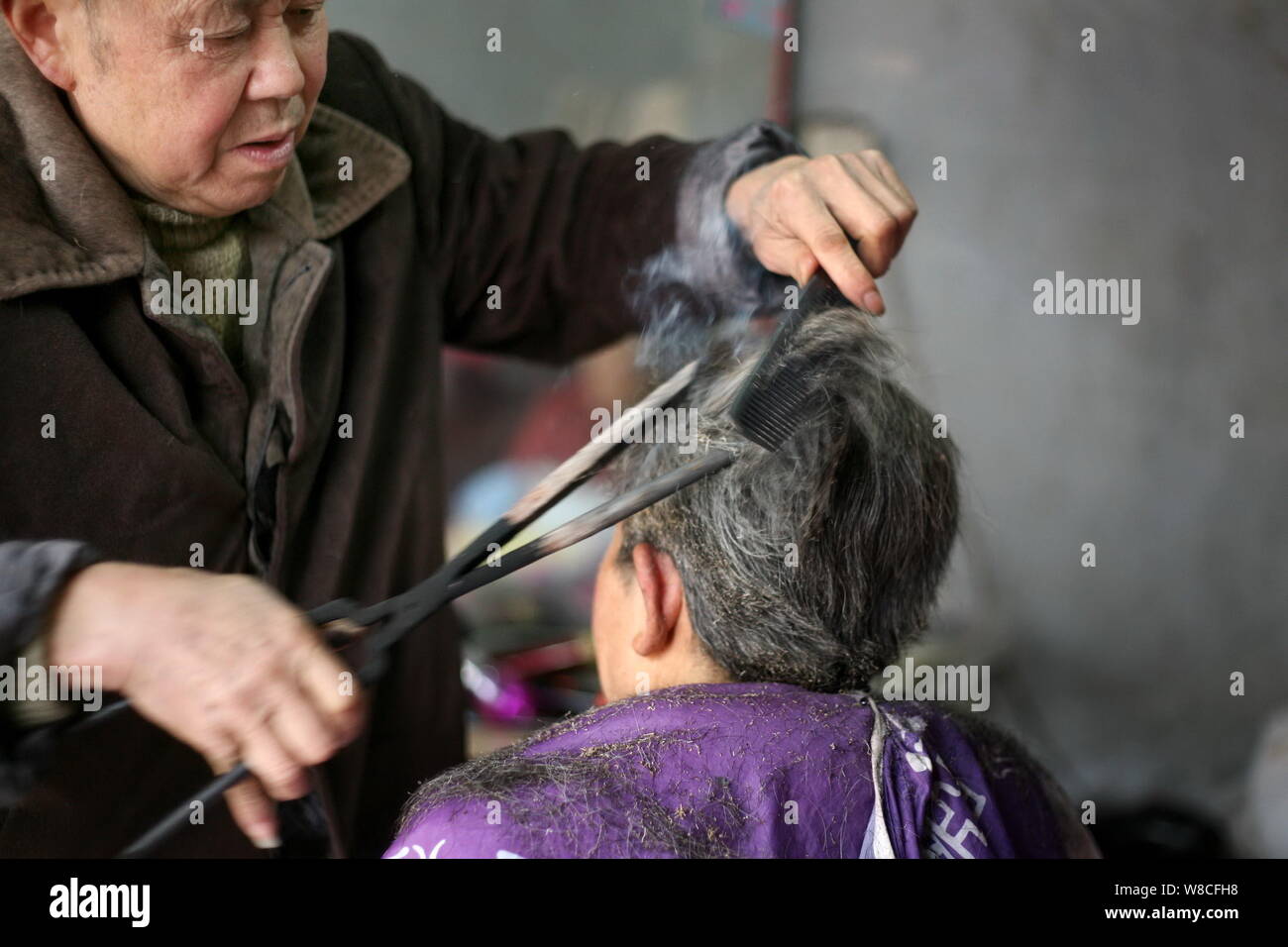 Chinese Barber Wang Weimei Left Uses A Pair Of Hot Fire Tongs To Perm The Hair Of A Customer At His Shop In Jinshi Town Santai County Mianyang Cit Stock Photo