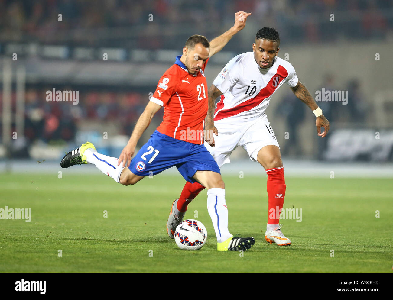 Chile's Marcelo Diaz, left, shoots against Peru during the Copa America 2015 semi-final soccer match between Chile and Peru at the National Stadium in Stock Photo
