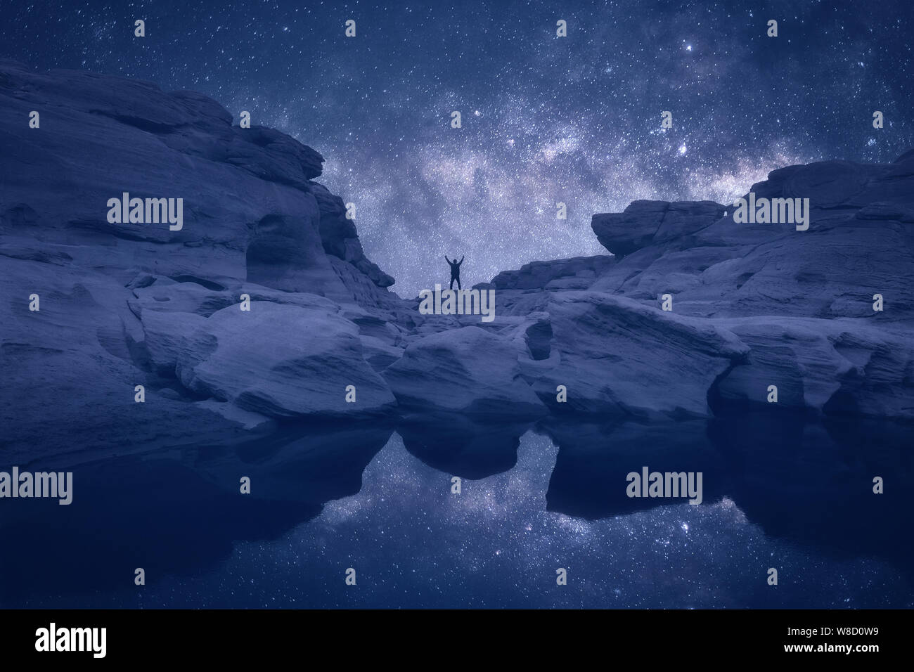 Night landscape with Milky Way. Silhouette of a standing young man with ...
