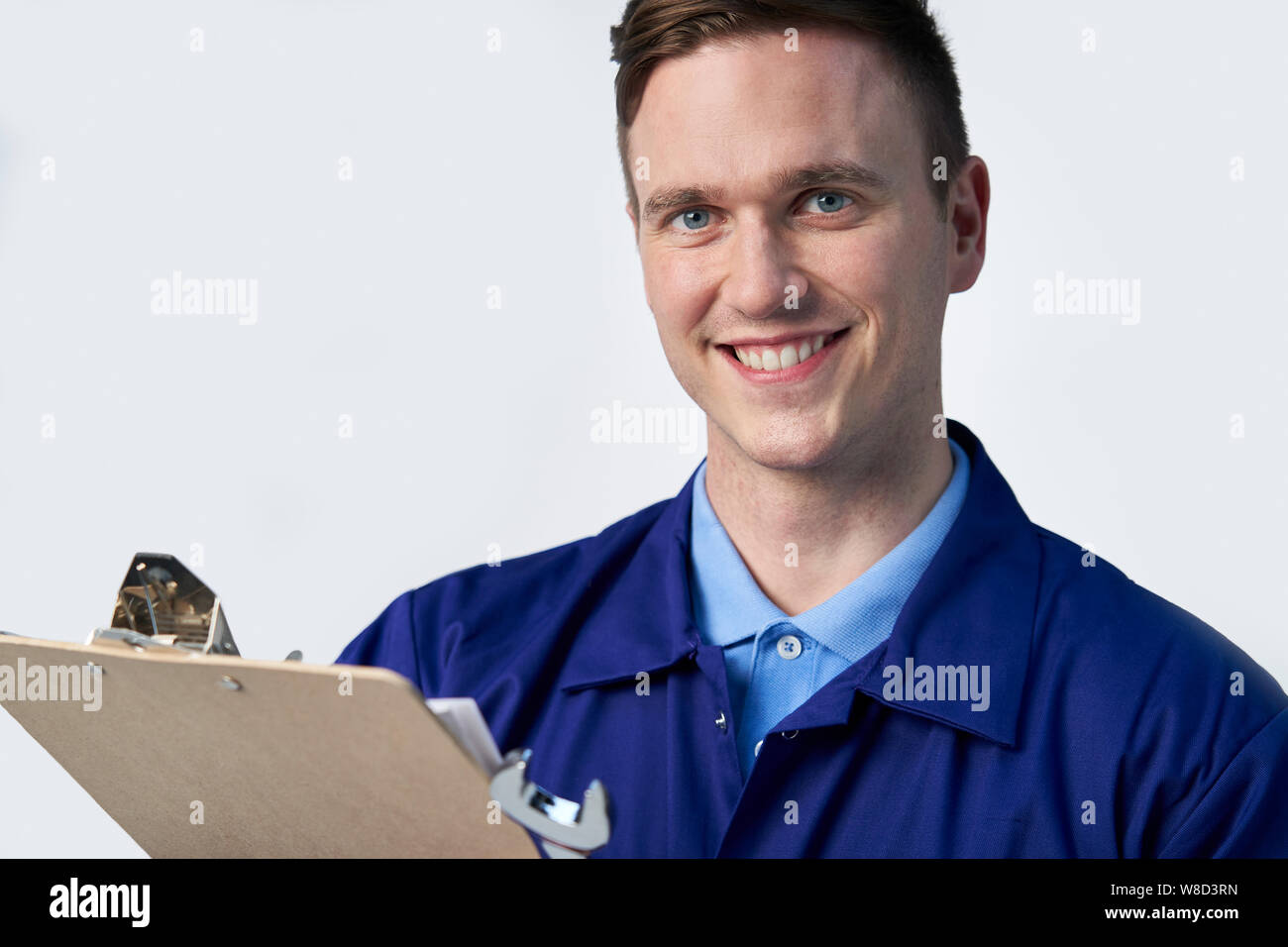 Studio Portrait Of Male Engineer With Clipboard And Spanner Against White Background Stock Photo
