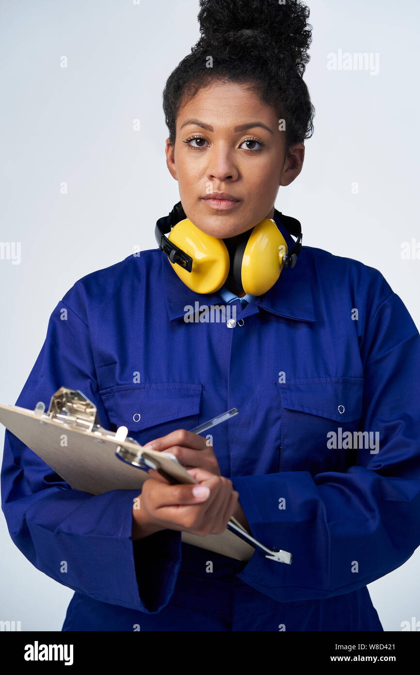 Portrait Of Studio Shot Of Female Engineer With Clipboard And Spanner Against White Background Stock Photo