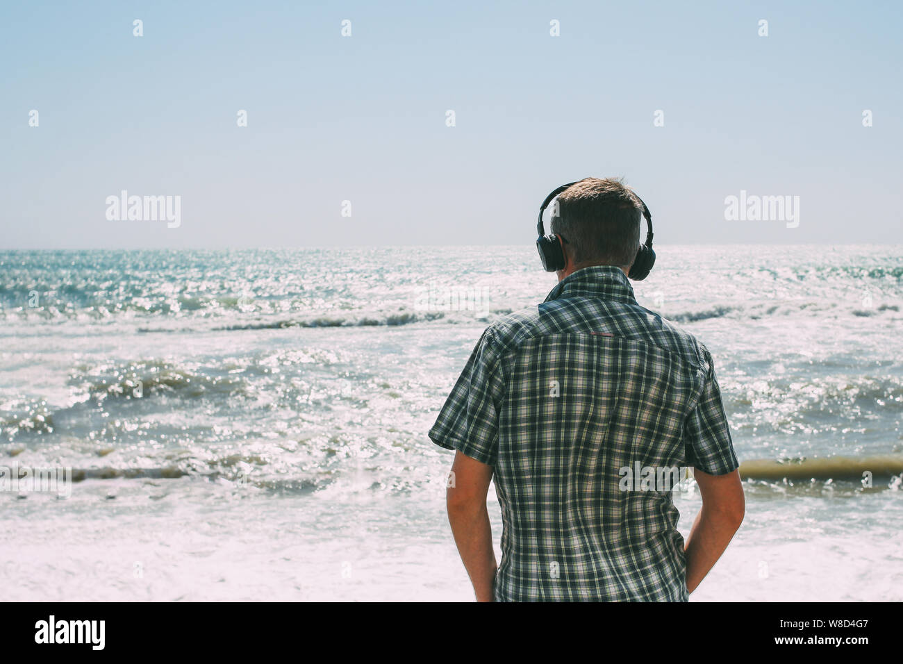 Adult man with headphones looking at the stormy sea Stock Photo